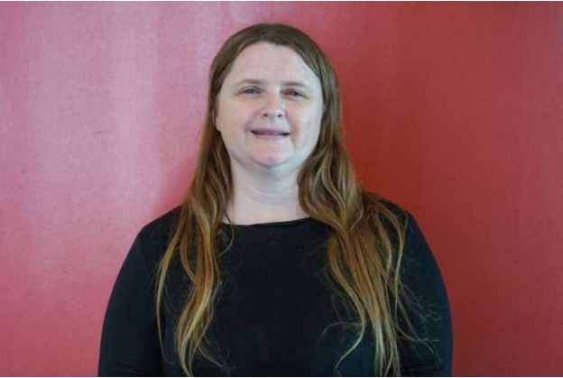 A white woman with long bronde hair against a red background